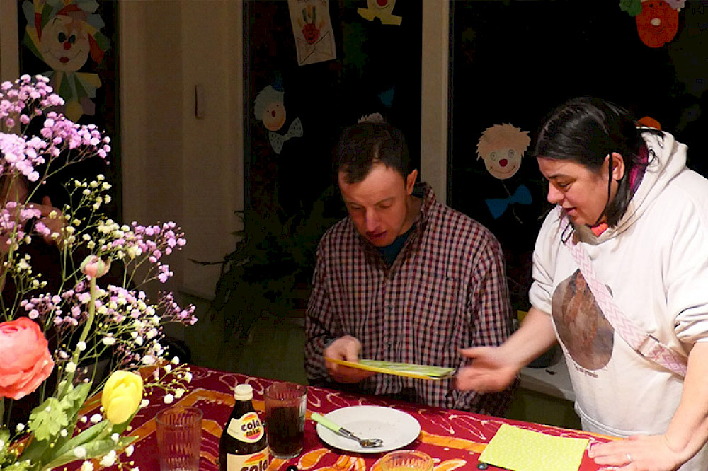 Bild zeigt zwei Personen beim Tischdecken.